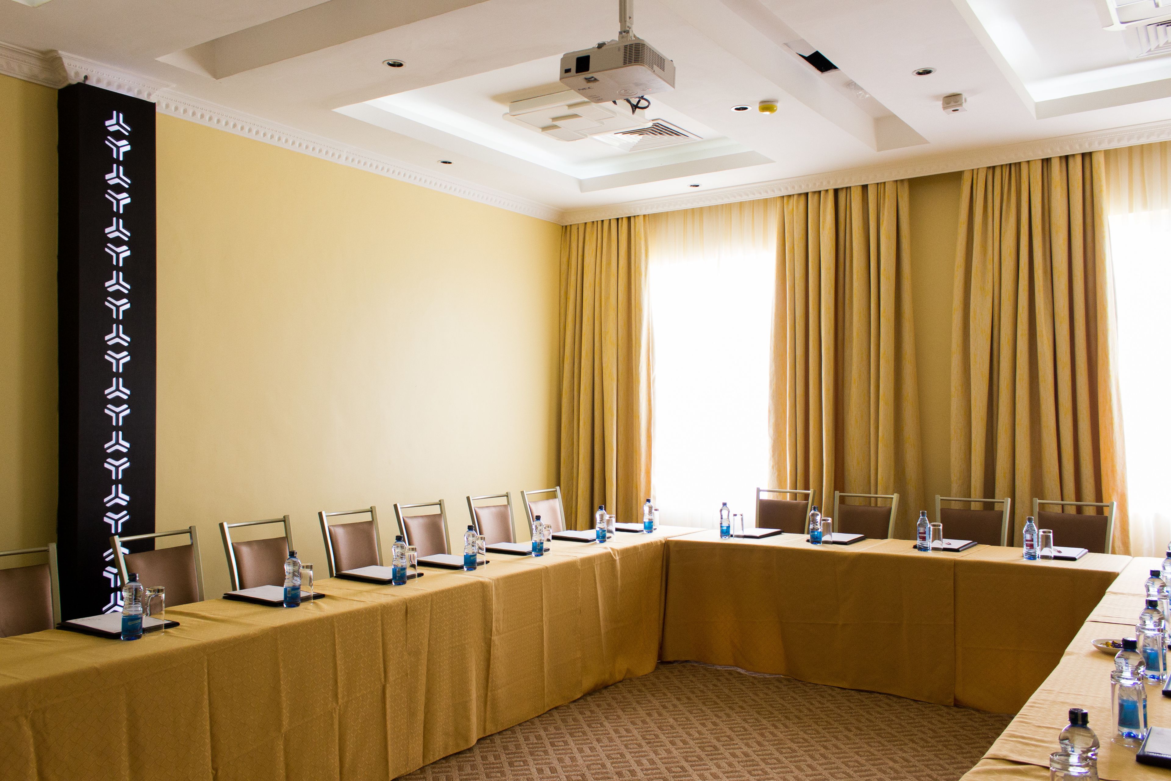 A conference room with a long table, chairs, laptops, water bottles, and a projector.