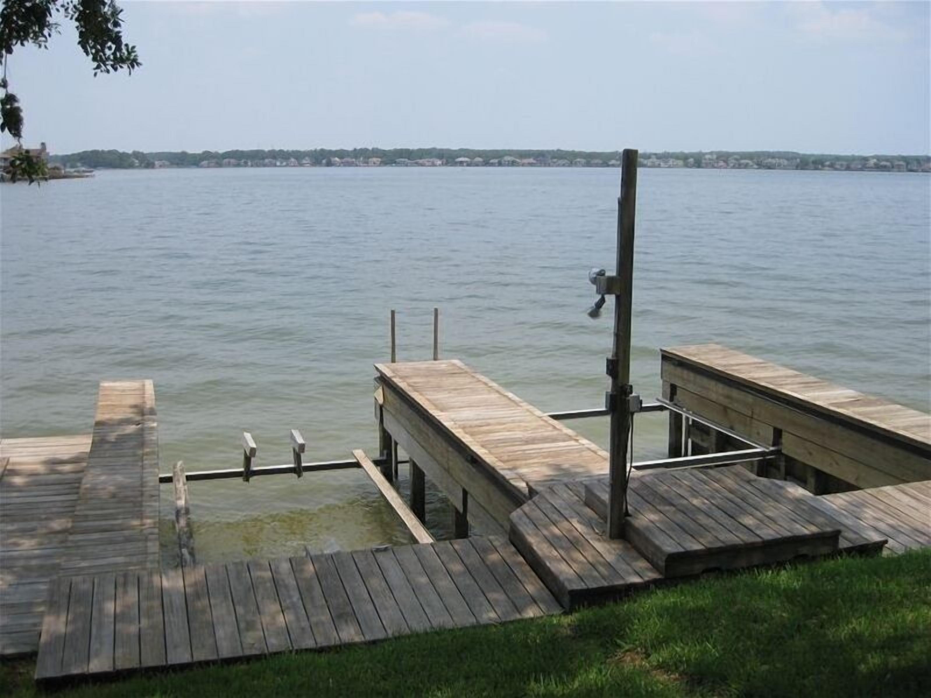 Une jetée en bois s’étendant dans un lac paisible, avec une zone herbeuse au premier plan.