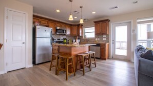 Una cocina moderna con armarios de madera, un refrigerador de acero inoxidable, un microondas integrado y una isla grande con taburetes de bar.