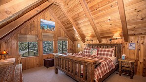 A cozy wooden cabin bedroom with a bed, a nightstand, a lamp, and a window with a scenic view. - Edelweiss Escape by Hauserman Rental Group (Tahoe City)