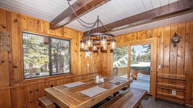 A wooden interior with a large dining table, benches, and a chandelier. - Edelweiss Escape by Hauserman Rental Group (Tahoe City)
