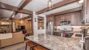 A spacious kitchen with granite countertops, stainless steel appliances, and wooden cabinets. - Edelweiss Escape by Hauserman Rental Group (Tahoe City)