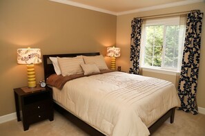 Cozy bedroom with a large bed, nightstand, and window with floral curtains.
