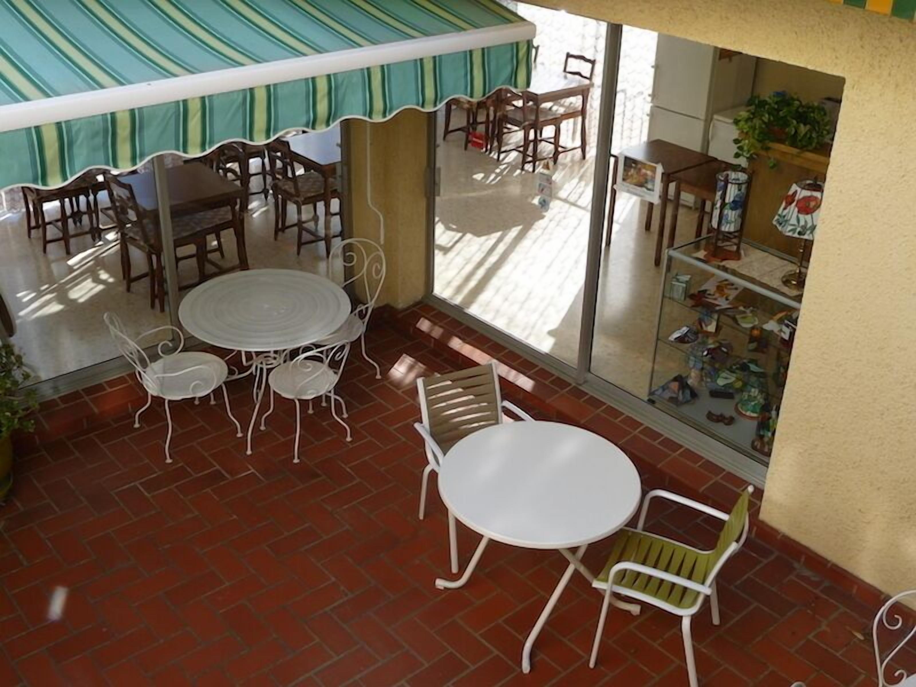 An outdoor patio with a round table and chairs, a glass door leading to an interior space, and a brick floor.