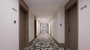 A hotel hallway with a patterned floor, numbered doors, and a straight path leading to the end. - Prolit Lanke Hotel (Chengdu)