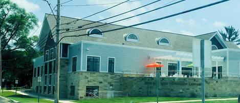 A two-story building with a stone facade, large windows, and a flat roof.