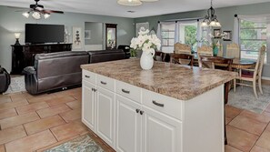 A kitchen with a granite countertop, white cabinets, and a dining area with a wooden table and chairs.