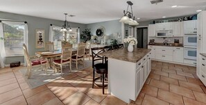 A spacious kitchen with white cabinets, a large island, and a dining area with a table and chairs.