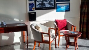 A hotel room with a desk, a chair, a small table, and a wall adorned with framed pictures of ocean scenes. - Kaikoura Quality Suites (Kaikoura)