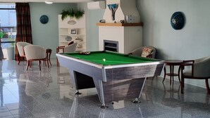 A pool table in a well-lit room with a fireplace, seating area, and decorative items. - Kaikoura Quality Suites (Kaikoura)