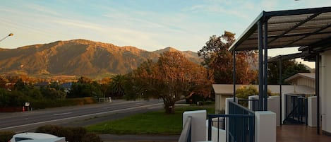 A building with a covered outdoor area and a view of a road and mountains in the background.