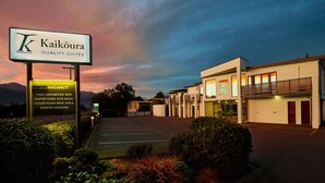 A hotel with a sign indicating 'Kaikoura Quality Suites' and amenities like free unlimited WiFi, super king size beds, a courtyard/BBQ area, and onsite parking. - Kaikoura Quality Suites (Kaikoura)