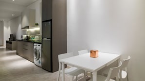 Een moderne keuken met een ingebouwde wasmachine, een koelkast en een eethoek met tafel en stoelen.