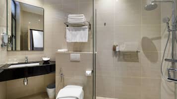 A modern bathroom with a glass-enclosed shower, a sink with a black countertop, and a toilet with a towel on top.