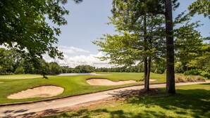 Un parcours de golf avec des bunkers de sable, un ciel dégagé et des arbres.