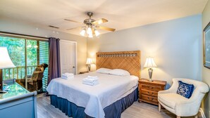 Une chambre à coucher comprenant un lit, deux tables de chevet, une chaise, un bureau et un ventilateur de plafond.