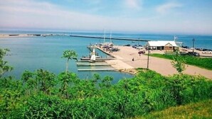 Un puerto marítimo costero con barcos amarrados, un pequeño edificio y cielo despejado.