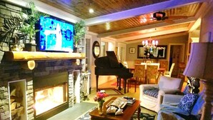 Un salón acogedor con chimenea, televisor, piano y asientos cómodos.