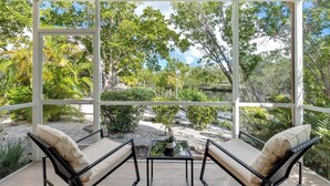 A conservatory with a view of a garden and a body of water. - Casa Largo (Key Largo)