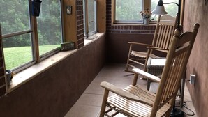 Quarto com janelas amplas, uma cadeira de balanço e um abajur.
