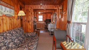 A cozy cabin interior with a patterned sofa, a chess table, and a kitchen area in the background. - Lakeview cabin on stunning Lake Vermilion (Tower)