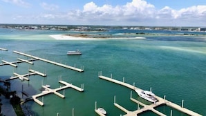 A marina with multiple docks and boats, a clear sky, and a distant shoreline with buildings. - Renovated Caribe Penthouse 3/3 Sleeps 12 (Orange Beach)