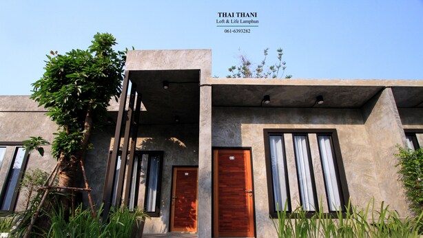 A modern building with two wooden doors, a concrete facade, and a clear sky. - Thai Thani Loft & Life Lamphun (Lamphun)