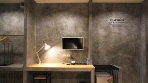 A modern workspace with a desk, a computer monitor, a desk lamp, and a small trash bin. - Thai Thani Loft & Life Lamphun (Lamphun)