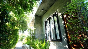 A pathway flanked by lush greenery leading to a building with a concrete facade and large windows. - Thai Thani Loft & Life Lamphun (Lamphun)