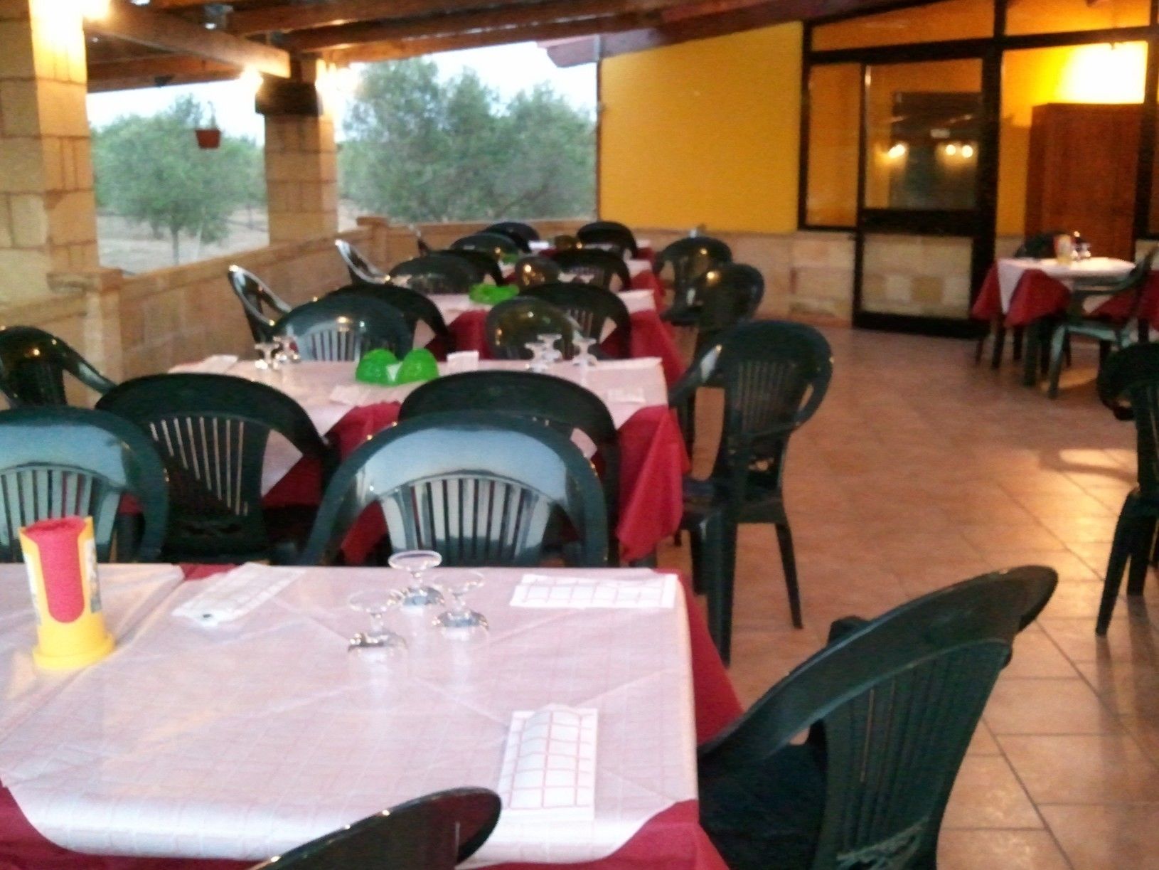 Un restaurant amb terrassa, taules cobertes amb gots vermells i caires negres.