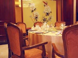 A dining table set for four with chairs, a floral wall decoration, and a chandelier.
