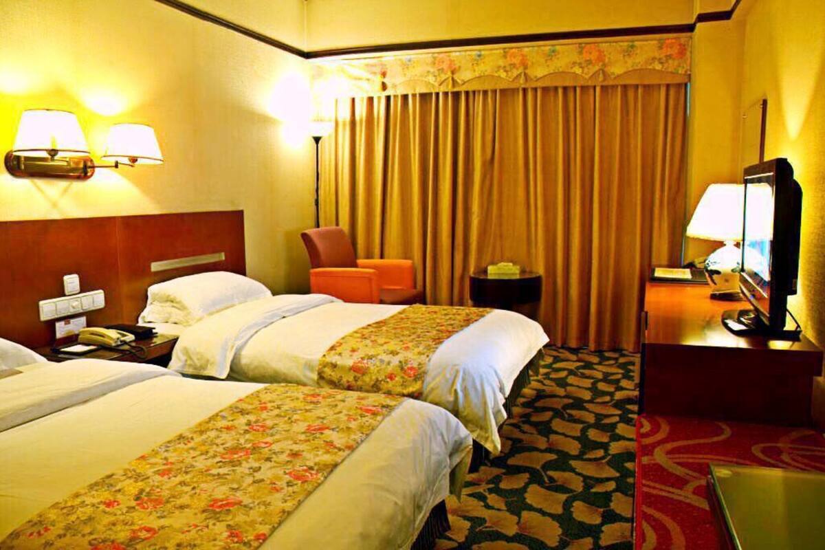 Una habitación de hotel con dos camas, un escritorio, una silla, un televisor y un teléfono.