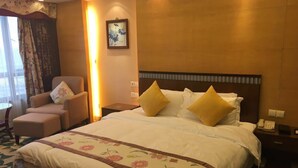Una habitación de hotel con una cama grande, una silla, una mesita de noche, una lámpara y un cuadro en la pared.