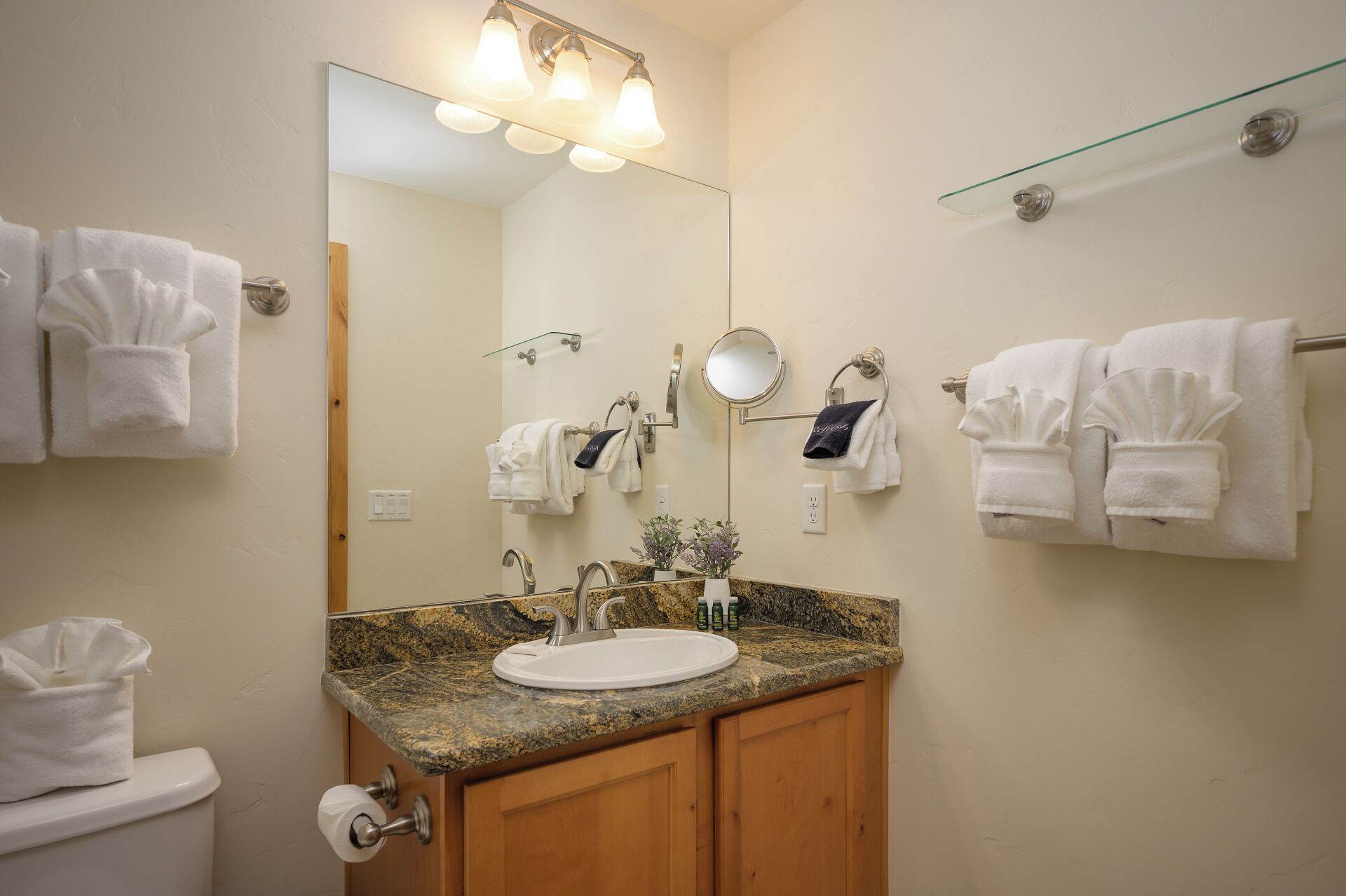 Un baño con lavamanos, espejo, toallero y retrete.