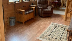 A wooden cabin interior with a sofa, armchair, and a rug. - Bearadise On the Thornapple River (Ladysmith)