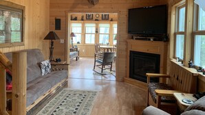 A wooden cabin interior with a mounted deer head, a fireplace, a television, and a cozy seating area. - Bearadise On the Thornapple River (Ladysmith)