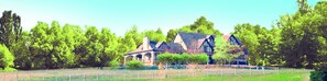 A large house with a garden, a fence, and trees.
