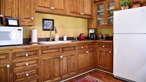 Una cocina con armarios de madera, microondas, fregadero y refrigerador.