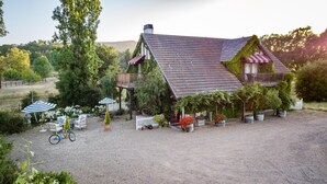 Una casa rústica con camino de grava, mobiliario exterior y plantas en macetas.