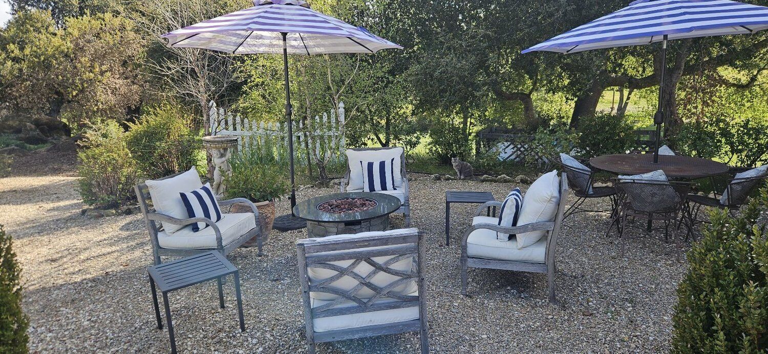 Eine Terrasse im Freien mit Sitzgelegenheiten, Sonnenschirmen und einer Feuerstelle.