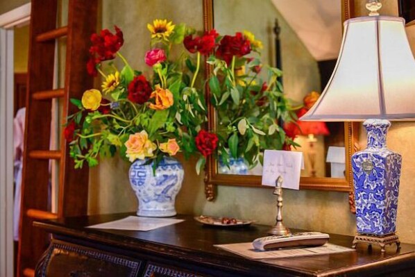 Un escritorio con un florero, una lámpara y un espejo.