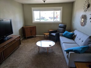 Relax in this inviting living room with a flat-screen TV, comfortable sofa, and a round coffee table.