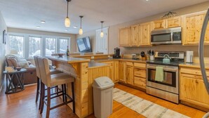 A modern kitchen with wooden cabinets, stainless steel appliances, and a bar area.