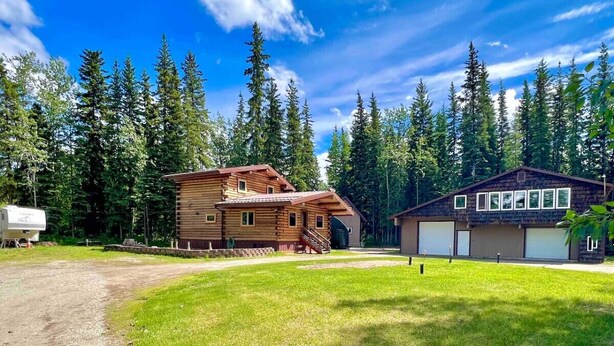 A cabin with a wooden exterior, a covered porch, and a garage.