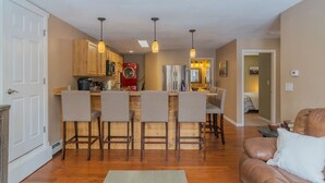 A modern kitchen with wooden bar stools, a red washing machine, and pendant lighting.