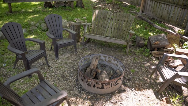 A fire pit surrounded by Adirondack chairs and a wooden bench in a garden setting. - Two Bed Two Bathroom Cabin with kitchenette area (Williams Bay)