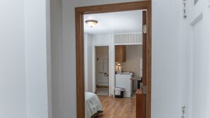 A narrow hallway leading to a bedroom with a bed and a small desk area. - Two Bed Two Bathroom Cabin with kitchenette area (Williams Bay)