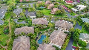 An aerial view of a residential area with houses, a swimming pool, and lush greenery.