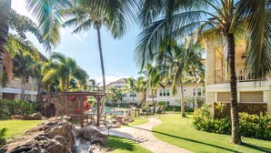 A resort with a pool, palm trees, and a stone pathway.