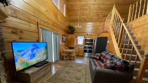 Ein gemütliches Blockhaus-Interieur mit Holzausstattung, einer Essecke, einer Küche und einer Treppe.